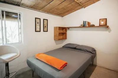 a bedroom with a bed with an orange blanket on it at Casa blanca, Refugio Natural Jacaranda in Cocorná
