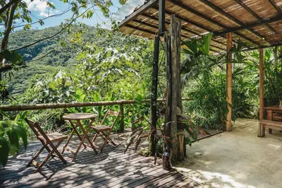 a porch with chairs and a table and a view at Casa blanca, Refugio Natural Jacaranda in Cocorná