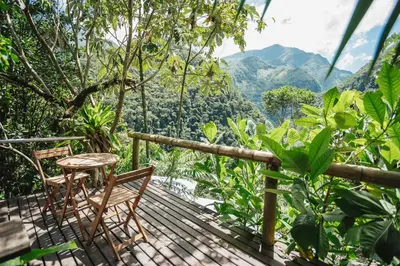 a wooden deck with two chairs and a table at Casa blanca, Refugio Natural Jacaranda in Cocorná