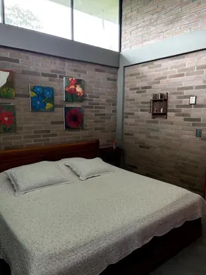 a bedroom with a bed and a brick wall at Casa de Campo in Manizales