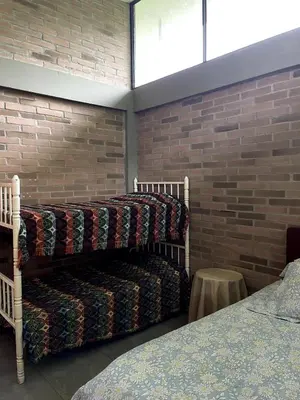 two beds in a room with a brick wall at Casa de Campo in Manizales