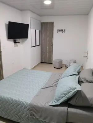 a bedroom with a bed with pillows and a flat screen tv at Hospedaje samfer in Envigado