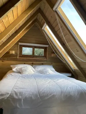 a bed in a attic with a window at Hermoso chalet en marinilla in Marinilla