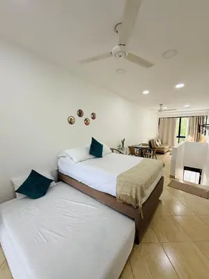 two twin beds in a bedroom with a living room at Alojamiento en Doradal - Apartaestudio central in Doradal