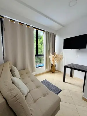 a living room with a couch and a flat screen tv at Alojamiento en Doradal - Apartaestudio central in Doradal