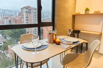 a table with two chairs and a table with wine glasses at Stadio Aparta Rosa Negra Suite in Medellín