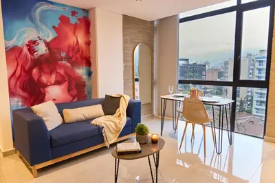 a living room with a blue couch and a painting at Stadio Aparta Rosa Negra Suite in Medellín