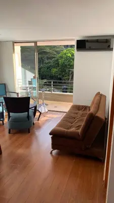 a living room with a couch and a table and a window at Pie de Cerro Condominium in Medellín