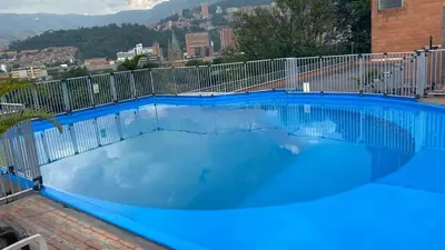 a large blue swimming pool with a fence at Pie de Cerro Condominium in Medellín