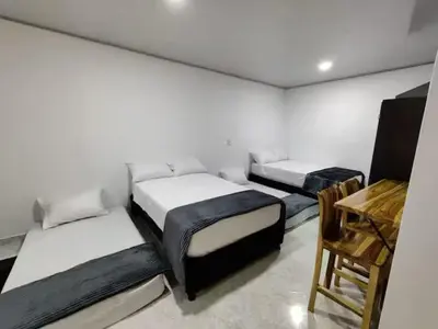 three beds in a room with a table and a chair at Apartahotel-sevilla in Medellín