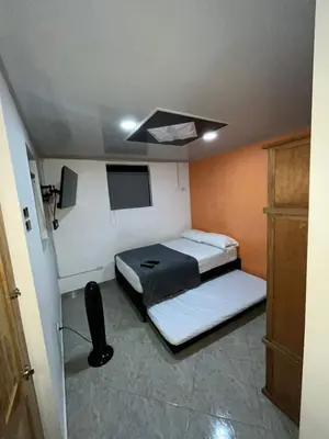 a small room with two beds and a tv at Apartahotel-sevilla in Medellín