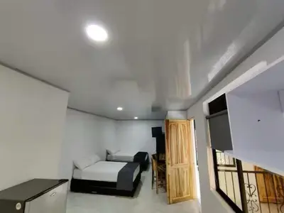 a room with a bed and a couch and a tv at Apartahotel-sevilla in Medellín