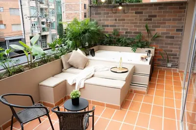 a balcony with a couch and a table and chairs at New Apt w private Jacuzzi & AC in Medellín