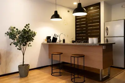 a kitchen with a counter with stools and a refrigerator at New Apt w private Jacuzzi & AC in Medellín