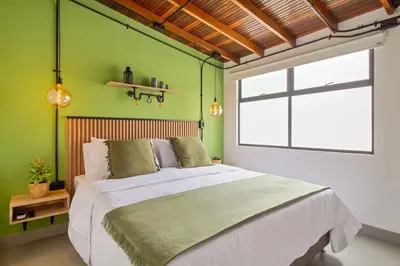 a bedroom with a large bed with a green wall at Studio30 A, Belen, Los Molinos in Medellín