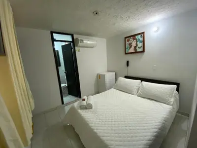 a bedroom with a white bed and a mirror at Hotel La Rosa in Mariquita