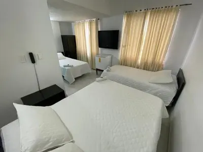 a hotel room with two beds and a television at Hotel La Rosa in Mariquita