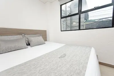 a bedroom with a white bed with a window at Novus Laureles in Medellín