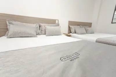 two beds in a hotel room with a mattressvisorvisor at Novus Laureles in Medellín