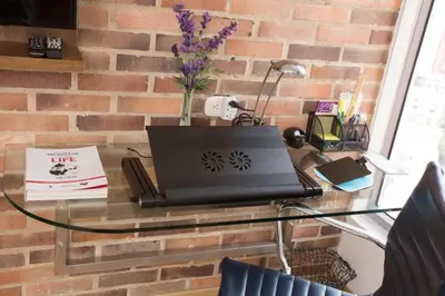 a glass table with a laptop on a brick wall at Luxury Laureles-LA 70-Medellin Stunner in Medellín