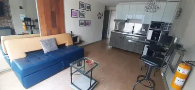 a living room with a blue couch and a kitchen at Luxury Laureles-LA 70-Medellin Stunner in Medellín