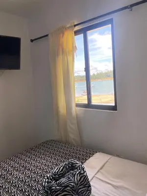 a bedroom with a window with a view of the beach at Hotel La Aldea in Guatapé