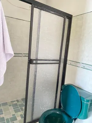 a shower with a blue toilet in a bathroom at Hotel La Aldea in Guatapé