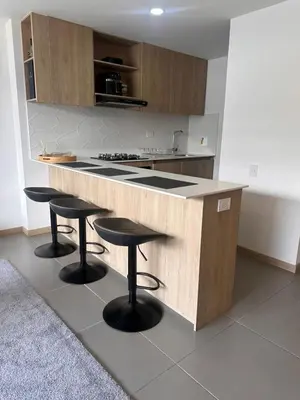 a kitchen with three bar stools and a counter at Apartamento en Medellín poblado in Medellín