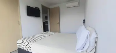 a bedroom with a white bed with a tv on the wall at Cold AC-fast Wi-Fi-great location-Medellin fun in Medellín