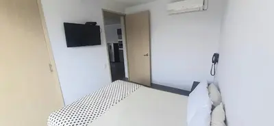 a bedroom with a white bed with a television on the wall at Cold AC-fast Wi-Fi-great location-Medellin fun in Medellín