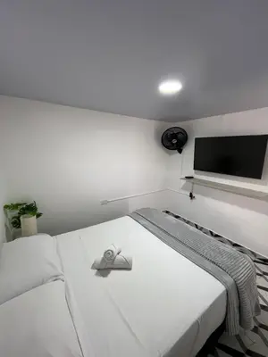 a white bedroom with a bed with a flat screen tv at Apartamento en Itagüí in Itagüí