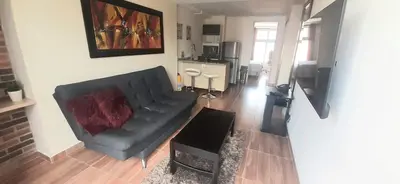 a living room with a black couch and a table at New comfortable Laureles Apartment Great location! in Medellín