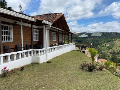 a house with a balcony with a table and chairs at Hermosa Finca Con Piscina y Jacuzzi in El Peñol