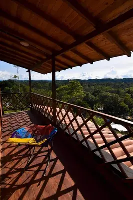 a chair on a balcony with a view of trees at Cabaña cerca a hacienda Nápoles in Doradal