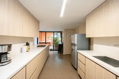 a kitchen with wooden cabinets and a refrigerator at 5BR Poblado Villa close to Lleras Jacuzzi Cinema AC in Medellín