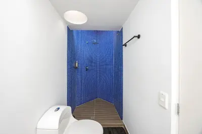 a bathroom with a toilet and a blue shower at 5BR Poblado Villa close to Lleras Jacuzzi Cinema AC in Medellín