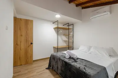 a bedroom with a bed with white sheets and a wooden floor at B3 4BR Poblado Penthouse wit AC and Jacuzzi in Medellín
