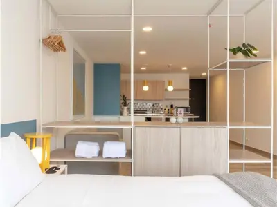 a bedroom with a white bed and a kitchen at Modern Loft in Laureles in Medellín