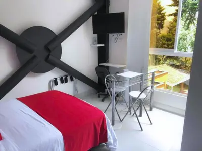 a bedroom with a red bed and a desk and a window at Mini Loft in Envigado in Envigado