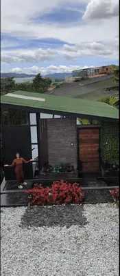 a person sitting on a bench in front of a house at Espectacular Cabaña en Rionegro Antioquia, vista paisajes in Rionegro