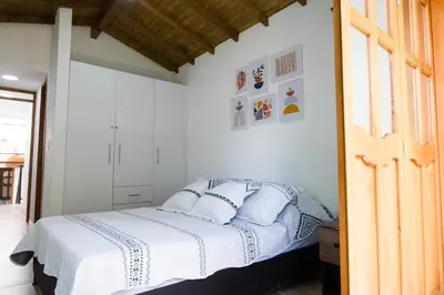 a bedroom with a bed with white sheets and pillows at Beautiful Modern House in Guatape! in Guatapé