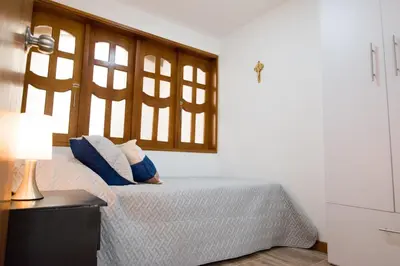 a bedroom with a bed with blue pillows and a window at Beautiful Modern House in Guatape! in Guatapé