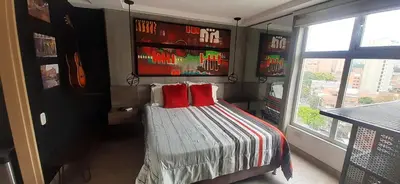a bedroom with a bed with red pillows and a window at Stylish Loft in Laureles-Gorgeous views & comfort in Medellín