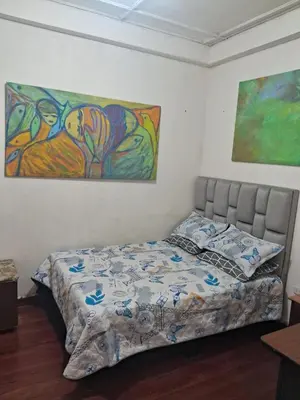 a bed in a bedroom with a painting on the wall at Hospedaje Parque Caldas Fundadores Manizales in Manizales