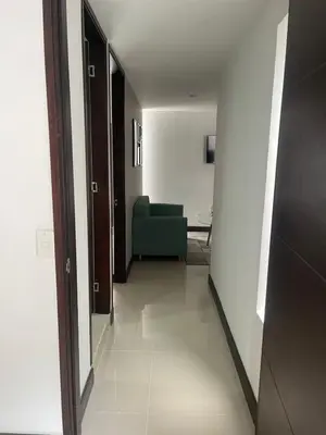 a hallway leading to a living room with a green couch at Apartamento familiar laureles 203 in Medellín