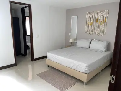 a white bedroom with a bed and a mirror at Apartamento familiar laureles 203 in Medellín