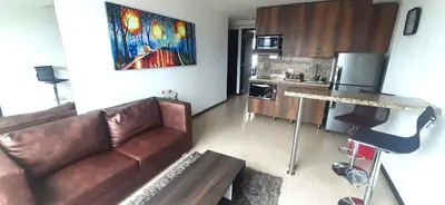 a living room with a brown couch and a kitchen at Penthouse Rooftop terrace Gem in the sky-Laureles in Medellín