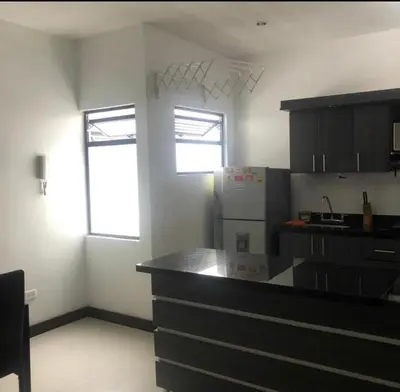 a kitchen with a black counter top and two windows at Apartamento con balcón y hamaca en zona rosa laureles 301 in Medellín
