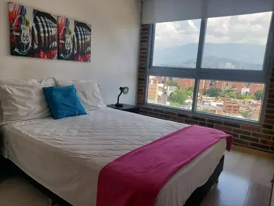 a bed in a room with two large windows at Best views in town, 14th floor Laureles Gem in Medellín