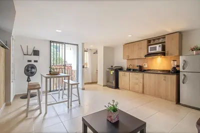 a large kitchen with wooden cabinets and a table at Hermoso apartamento en el centro in Medellín